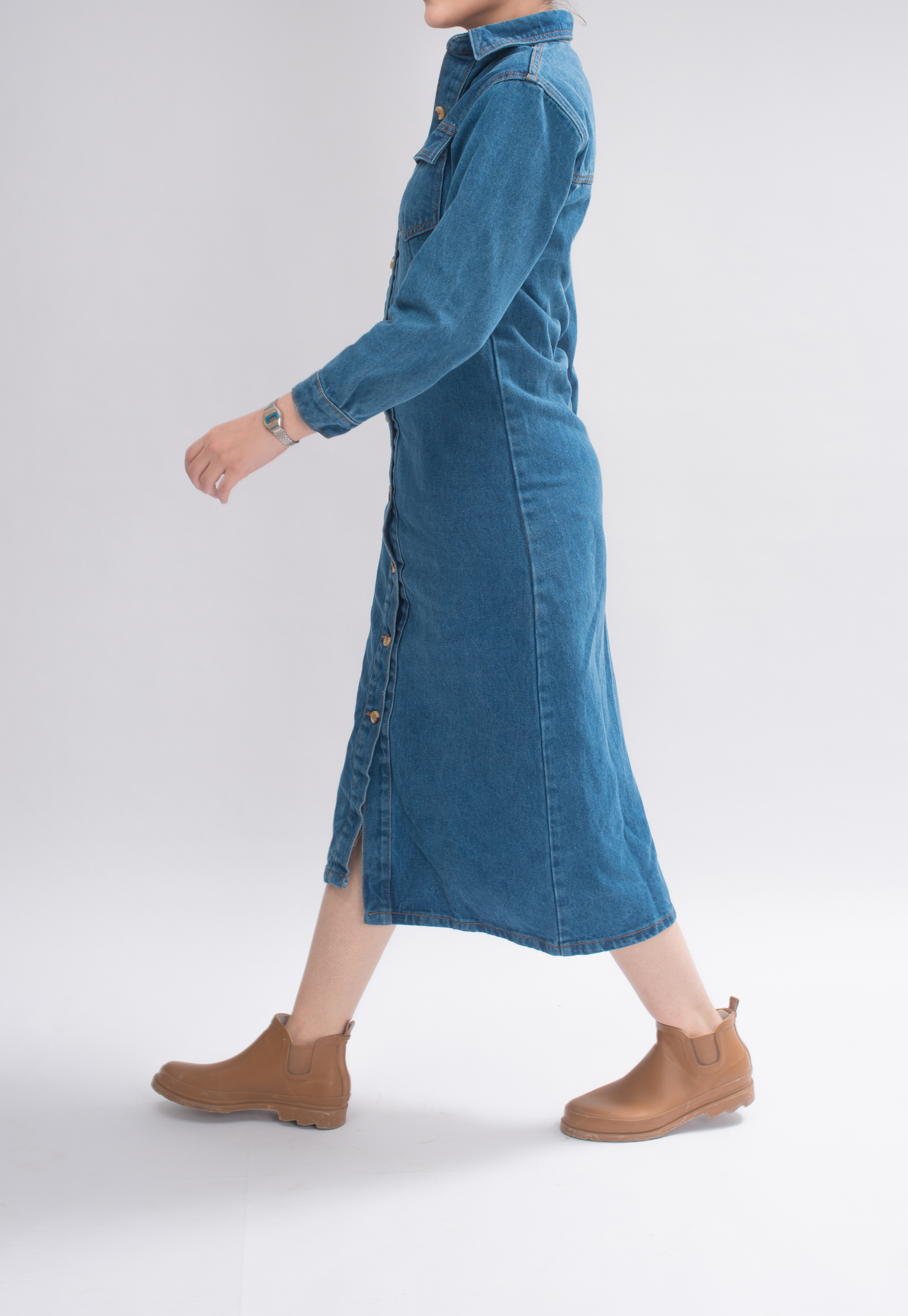 Side view of women’s long button shirt in denim, highlighting the loose fit and gathered seam at the waist.