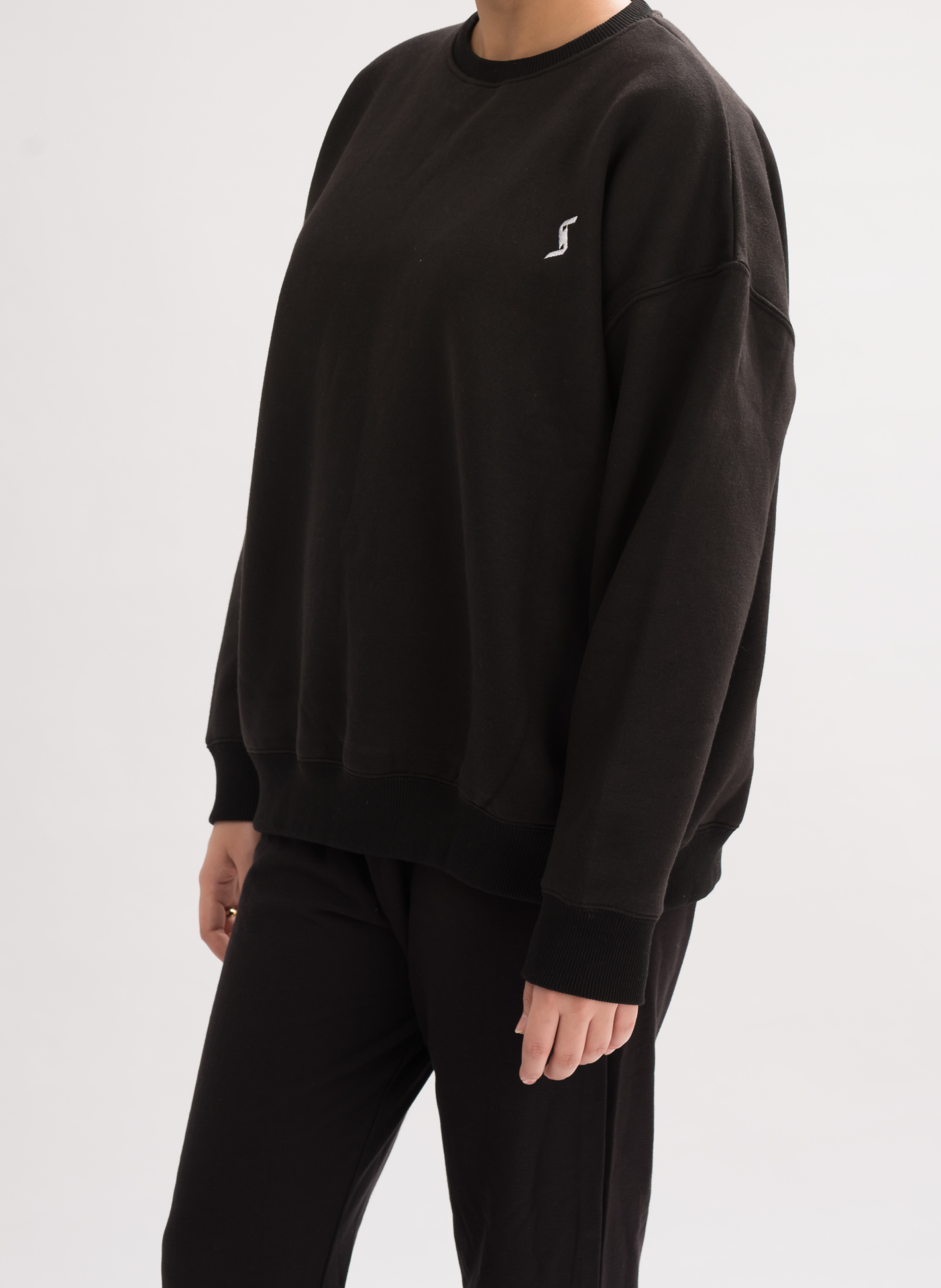 Side view of Women’s Oversized Crew Neck T-Shirt Dress in Black. Effortlessly chic with a crew neck and relaxed fit.