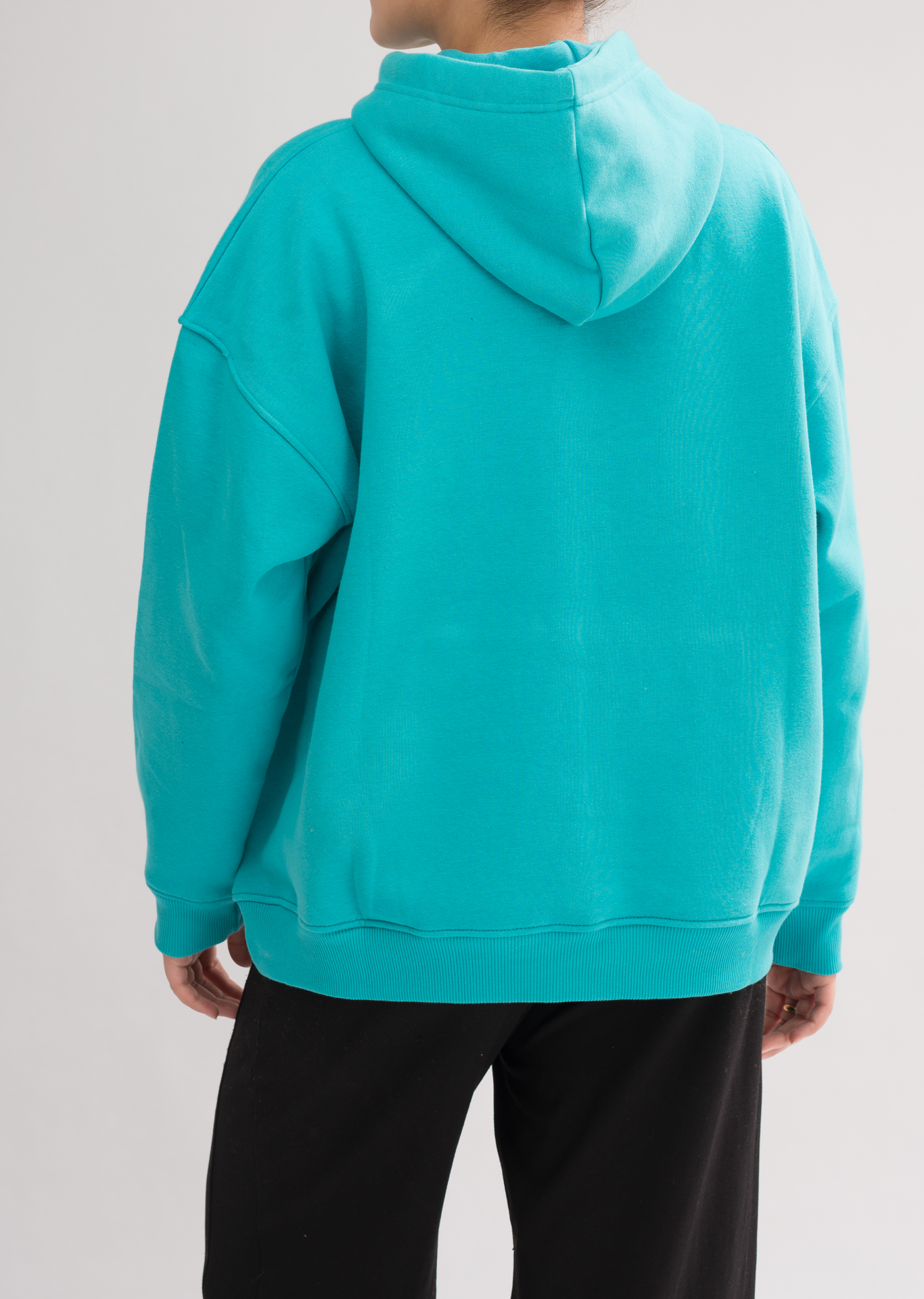 Back view of Women’s Classic Oversized Hoodie in Jade. Designed with a double-layered hood and dropped shoulders for a chic look.